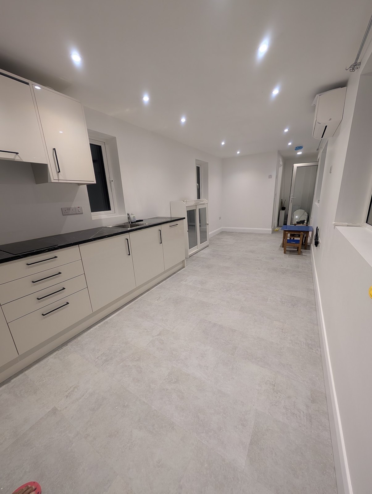 A long kitchen and living room with recessed ceiling lights